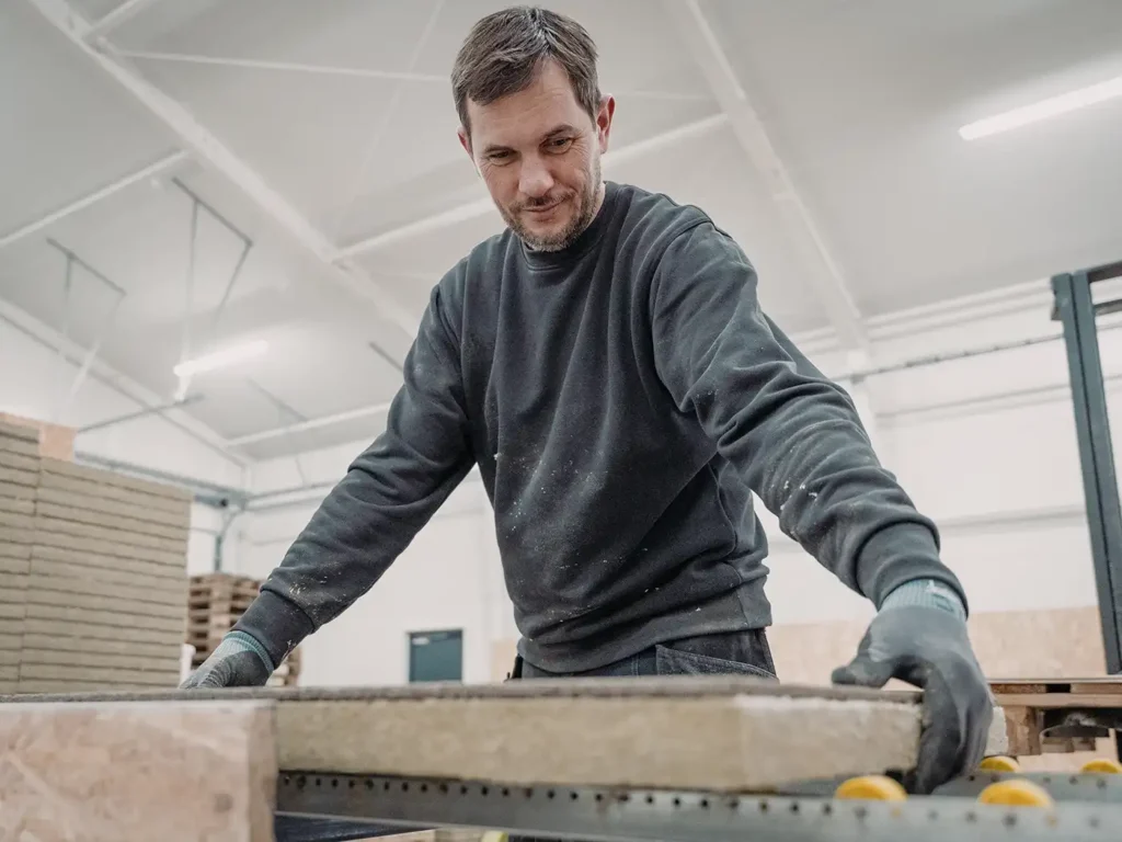 Employee handling a mineral wool acoustic panel in production at Hz Acoustic in Frederikshavn