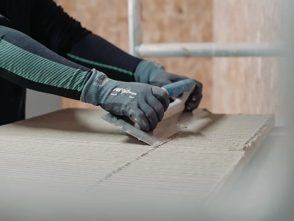 Installer applying adhesive with a notched trowel when gluing an acoustic panel